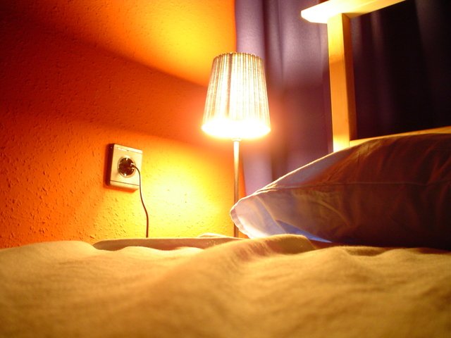 postel s rozsvícenou lampičkou
